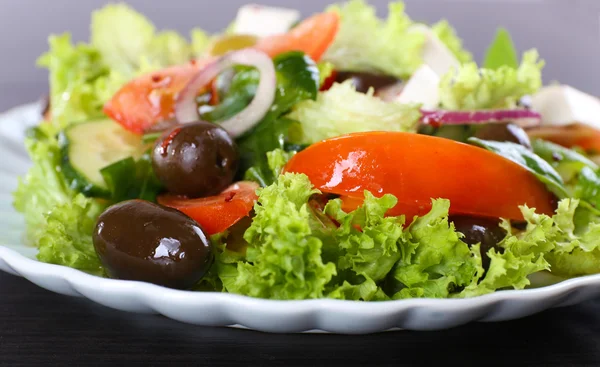 Griechischer Salat im Teller auf Holztischhintergrund — Stockfoto