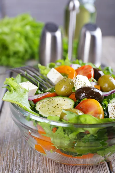 Greek salad in glass dish on wooden table background — Stock Photo, Image