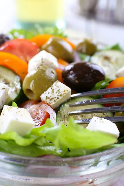 Греческий салат в стеклянной тарелке с вилкой, крупным планом — стоковое фото
