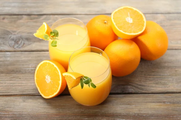 Copo de suco de laranja e fatias em fundo de mesa de madeira — Fotografia de Stock