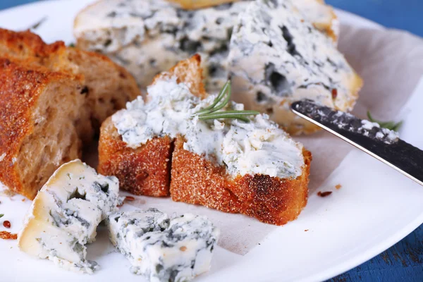 Queijo azul com raminhos de alecrim, pão e nozes na placa e cor de fundo de mesa de madeira — Fotografia de Stock