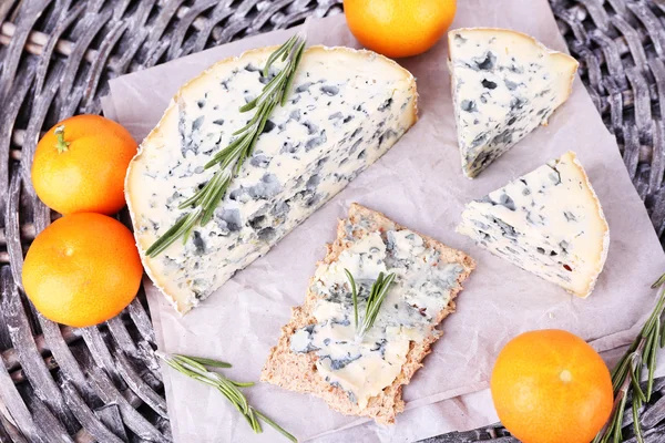 Blue cheese with sprigs of rosemary and oranges on wicker mat background — Stock Photo, Image