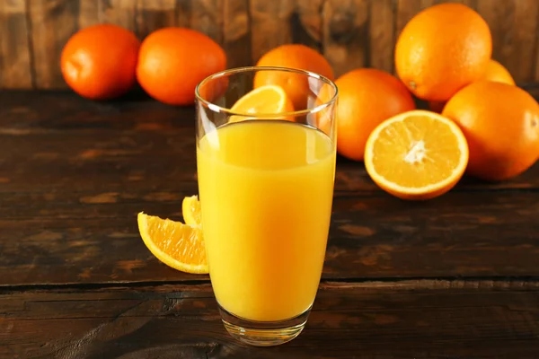 木製のテーブル背景にスライスでのオレンジ ジュースのガラス — ストック写真
