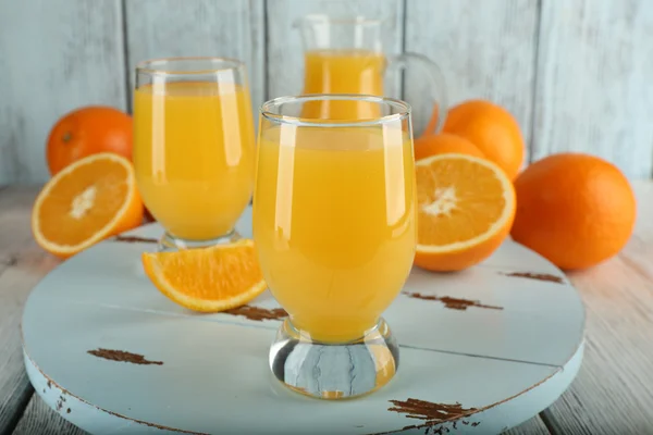 Bicchiere di succo d'arancia con fette su sfondo di legno a colori — Foto Stock