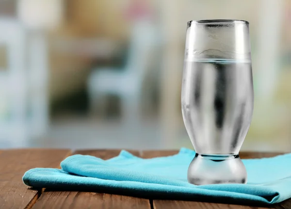 Glas Eiswasser auf Serviette auf Holztisch und leicht verschwommenem Hintergrund — Stockfoto