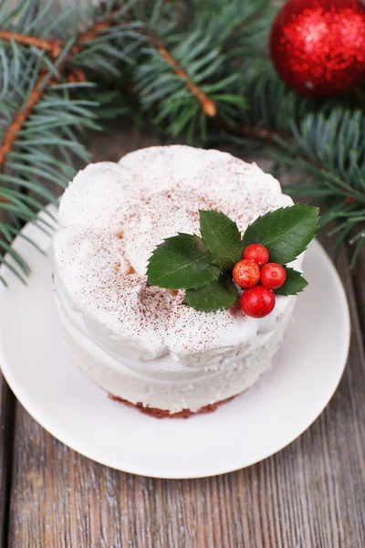 Delicioso pastel en platillo con acebo y baya en la decoración de Navidad y fondo de madera — Foto de Stock