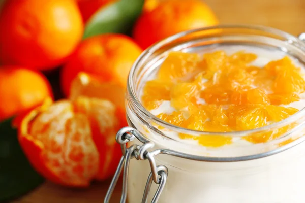 Sabroso postre de leche con trozos de mandarina fresca en frasco de vidrio, sobre fondo de madera —  Fotos de Stock