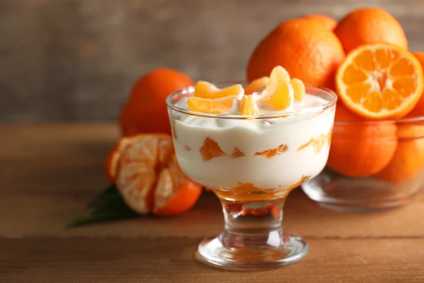 Sabroso postre de leche con trozos de mandarina fresca en tazón de vidrio, sobre fondo de madera — Foto de Stock