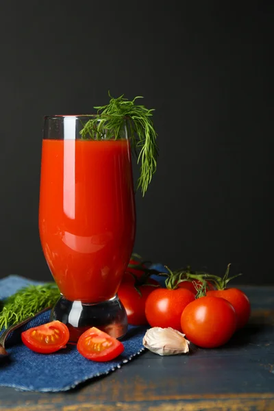 Szklanka soku pomidorowego smaczne i świeże pomidory na stole, na szarym tle — Zdjęcie stockowe