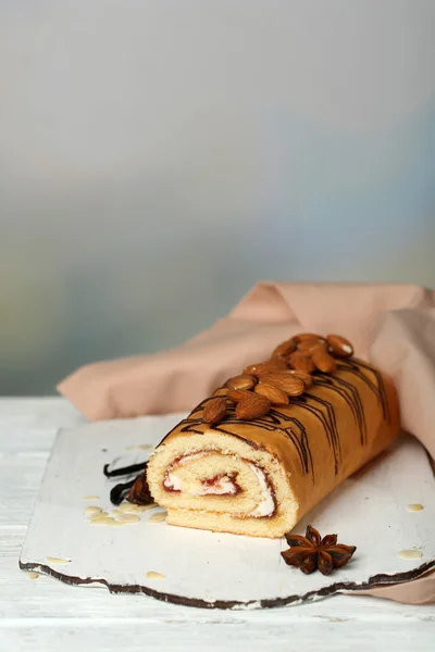 Délicieux gâteau roulé sur table en bois, sur fond clair — Photo