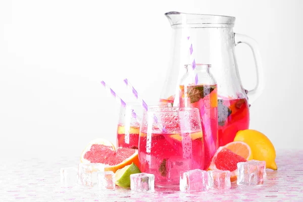 Rosa Limonade in Gläsern und Krug auf hellem Hintergrund — Stockfoto