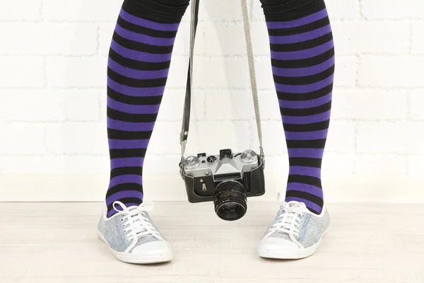 Девушка в кроссовках с ретро фотокамерой в номере — стоковое фото