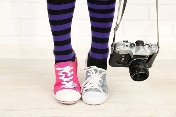 Flicka i sneakers med retro fotokamera i rum — Stockfoto