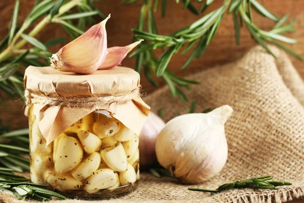 Canned garlic in glass jar on wooden background — Stock Photo, Image