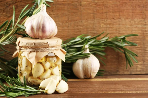 Ingeblikte knoflook in glazen pot op houten achtergrond — Stockfoto