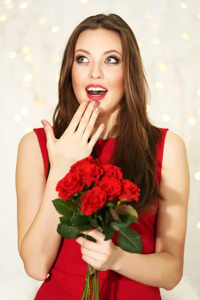 Lachende meisje met boeket van rode rozen op lichten achtergrond — Stockfoto