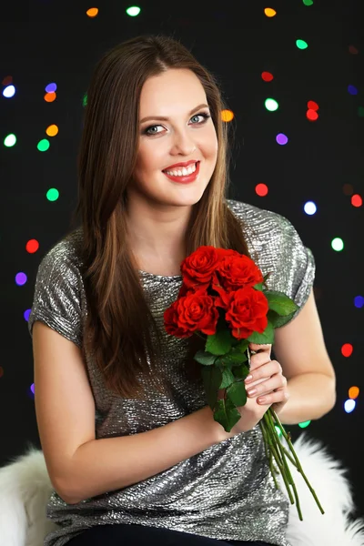 Ragazza sorridente con mazzo di rose rosse su sfondo luci — Foto Stock