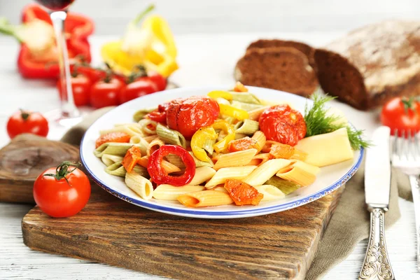 Těstovinový salát s paprikou, mrkev a rajčata na dřevěný stůl pozadí — Stock fotografie