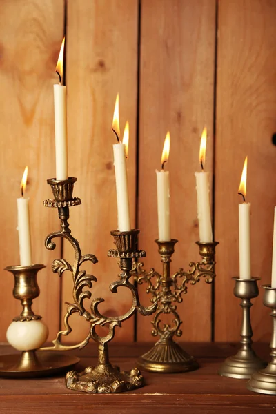 Retro candlesticks with candles on wooden background Royalty Free Stock Images