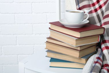 Yığın üzerinde tuğla duvar arka koltuğa Kupası ve ekose kitap