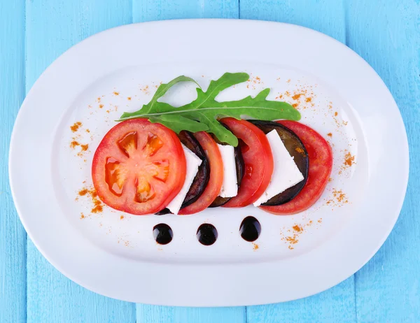 Aubergine salade met tomaat en feta kaas op plaat, op houten achtergrond — Stockfoto
