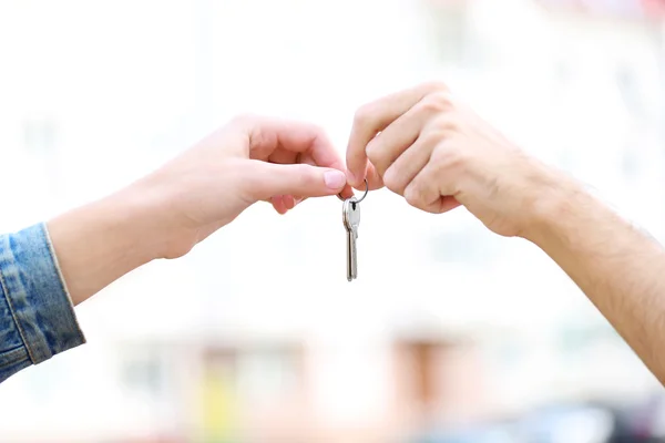 Man en vrouw handen houdt sleutels in de buurt van appartement huis — Stockfoto