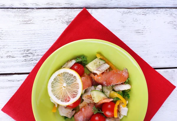 Färsk fisk sallad med grönsaker på tallriken på träbord närbild — Stockfoto