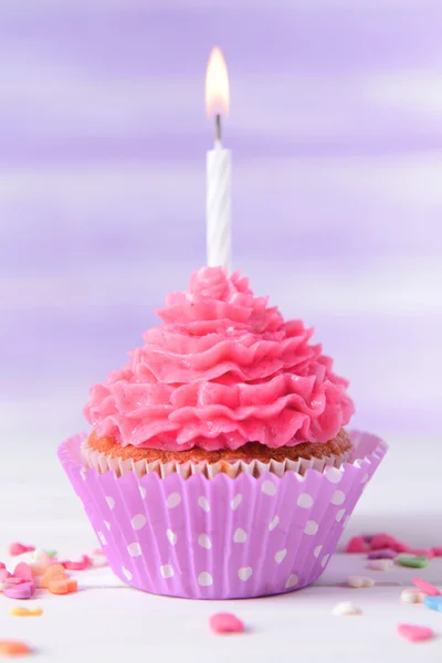 Delicioso cupcake de cumpleaños en la mesa sobre fondo púrpura claro —  Fotos de Stock