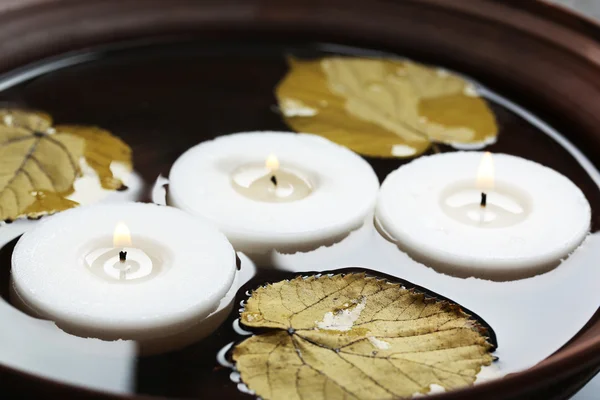Árbol velas blancas flotando con hojas en el agua en un tazón — Foto de Stock