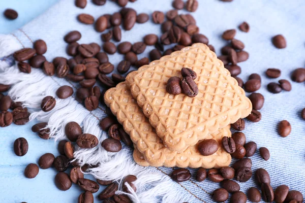 Shortbread Cookies mit verschütteten Kaffeebohnen auf blauem Holzhintergrund mit Jeansmaterial — Stockfoto