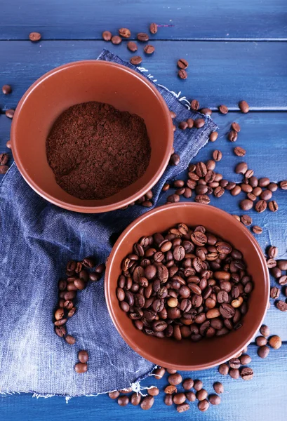 Zwei Schüsseln gemahlener Kaffee und Kaffeebohnen auf blauem Holzhintergrund mit Jeansmaterial — Stockfoto