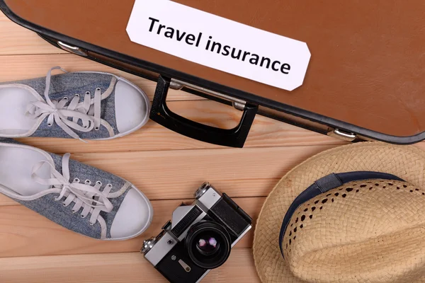 Suitcase and tourist stuff with inscription travel insurance on wooden background top view — Stock Photo, Image