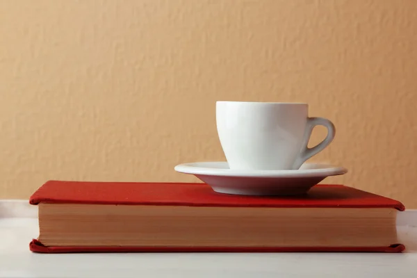 Tasse Heißgetränk auf Buch auf hellem Wandhintergrund — Stockfoto