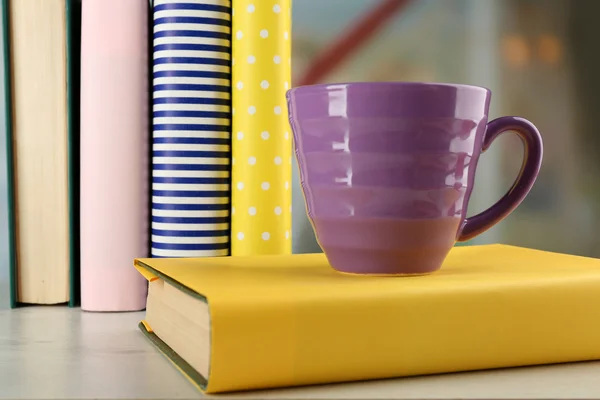 Кольорова чашка чаю з книгами на столі, на світлому розмитому фоні — стокове фото
