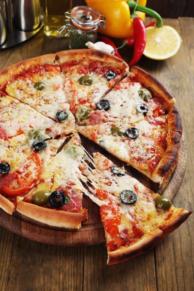 Pizza com queijo a bordo e fundo de mesa de madeira — Fotografia de Stock