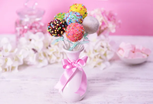 Sweet cake pops in vase on table on pink background — Stock Photo, Image
