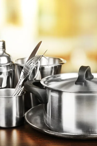 Stainless steel kitchenware on table, on light background — Stock Photo, Image