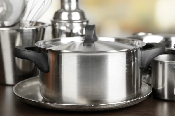 Stainless steel kitchenware on table, on light background — Stock Photo, Image