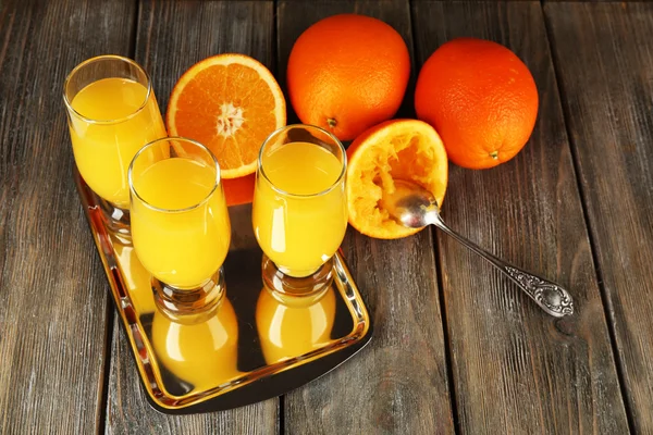 Copo de suco de laranja com fatias na bandeja de metal no fundo de madeira rústica — Fotografia de Stock