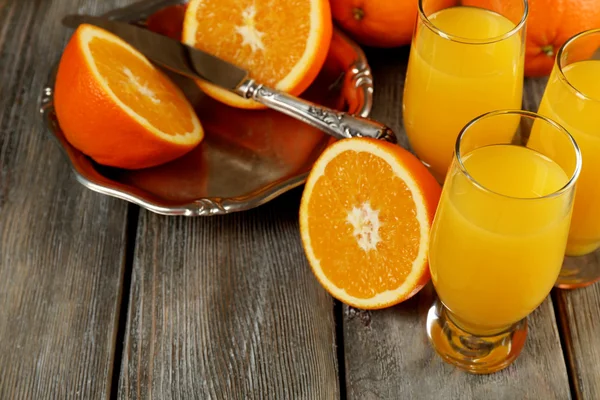 Glass of orange juice with slices on metal tray on rustic wooden table background — Stock Photo, Image