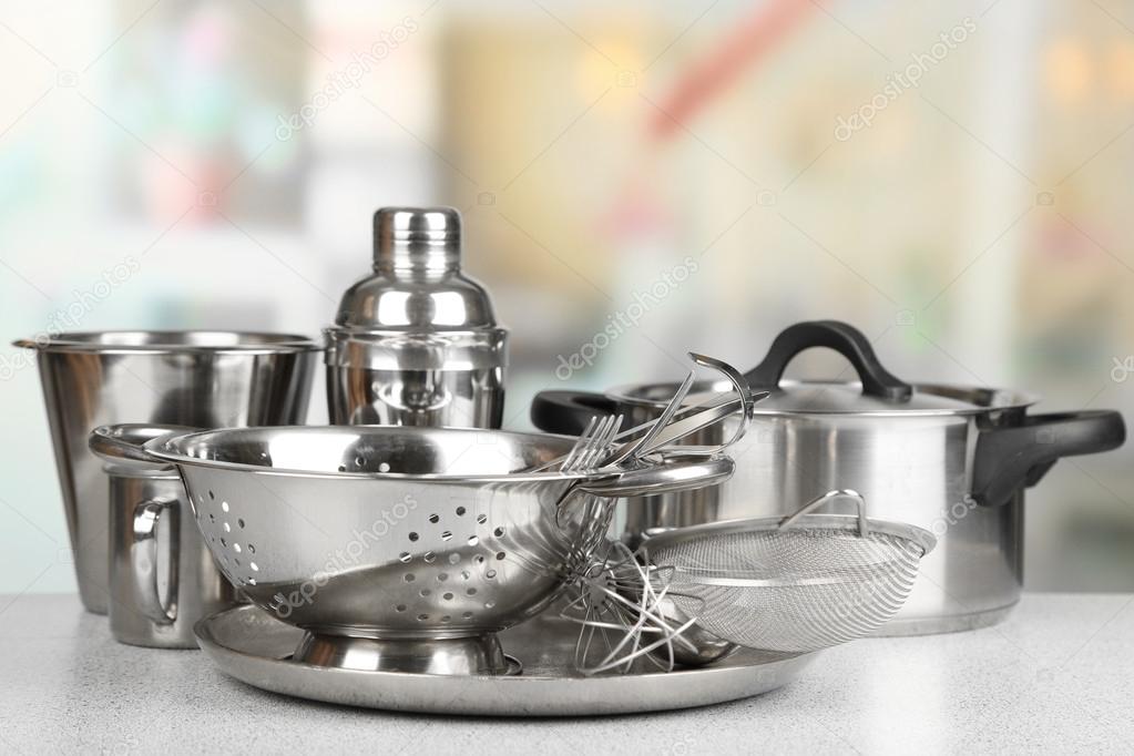 Stainless steel kitchenware on table, on light background