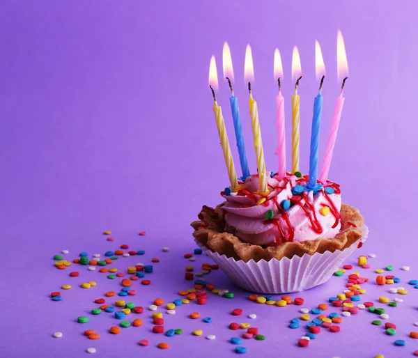 Bolo de xícara de aniversário com velas e brilhos coloridos no fundo roxo — Fotografia de Stock