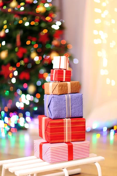 Scatole regalo su slitta sul pavimento in legno vicino all'albero di Natale, all'interno — Foto Stock