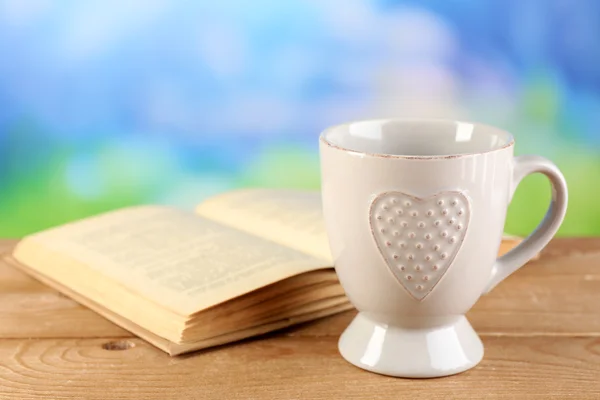 Cup of tea and book on table, on bright background — Stock Photo, Image