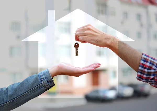 Mani maschili e femminili con chiavi circondate da forma di casa — Foto Stock