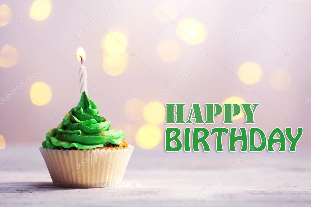 Delicious birthday cupcake on table on festive background
