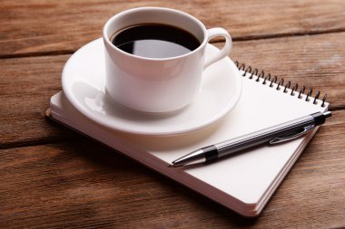 Fincan kahve üzerinde uçan daire ile defter ve kalem ahşap masa arka plan üzerinde