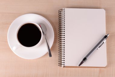 Fincan kahve üzerinde uçan daire ile defter ve kalem ahşap masa arka plan üzerinde