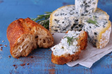 Mavi peynir dal biberiye ve kağıt ve renkli ahşap masa arka plan üzerine ekmek ile