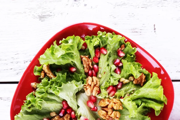 Fresh salad with greens, garnet and spices on plate on table close-up — Stock Photo, Image